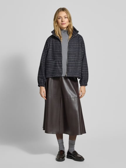 Modelka kobieca nosi Jacke mit Stehkragen Modell 'Mae' od LOLLYS LAUNDRY, ciemny wzór w kratę, luźny krój, dwie kieszenie, gumowe mankiety, pełny przód, zdjęcie całej sylwetki z przodu.