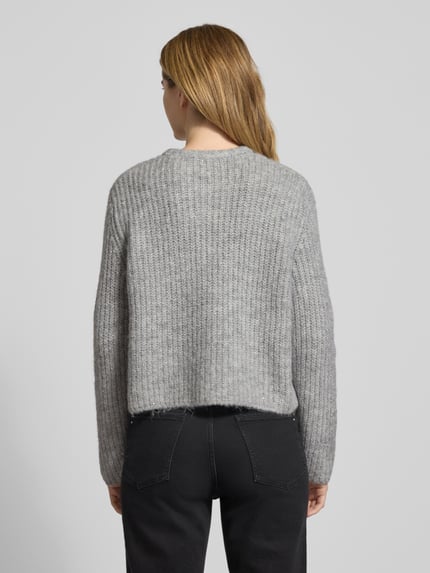 Frauenmodel trägt Strickjacke mit Rundhalsausschnitt Modell 'TIAH' von Someday, grauer Material-Mix mit Woll-Anteil, Regular-Fit, Knopfleiste, Rückenlänge bei Größe 36: 51 cm, Ärmellänge: 62 cm, Ganzkörperansicht Rückansicht.