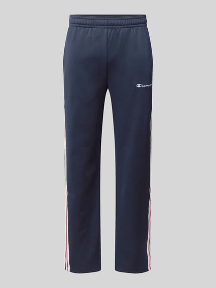 Produktfoto, Sweatpants mit Bordüre von Champion in Dunkelblau mit weiß-roten Seitenstreifen, gerader Schnitt, elastischer Bund, Baumwoll-Material-Mix, Label-Stitching, seitliche Eingrifftaschen, Innenbeinlänge 76 cm bei Größe M.