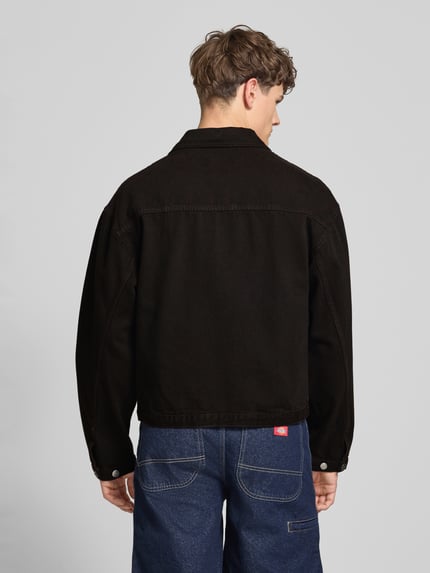 Männermodel trägt schwarze Jeansjacke mit Knopfleiste Modell 'FREELAND' von Edwin aus Reine Baumwolle, Relaxed-Fit, Rückenansicht Ganzkörperansicht. Kontext: Rückenlänge bei Größe M 65 cm, Schulterbreite 56 cm, Brustweite 58 cm, Ärmellänge 62 cm.