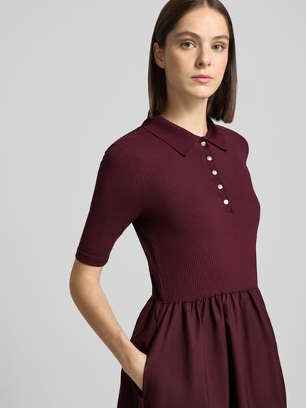 Frauenmodel trägt Midikleid mit Polokragen von Tommy Hilfiger in dunklem Burgunderrot, strukturierte Oberfläche, Nahaufnahme Oberkörper.