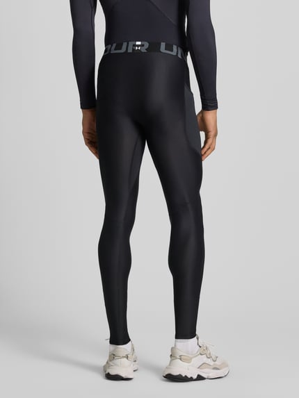 Männermodel trägt Leggings mit Beintasche von Under Armour in Schwarz mit Elastischer-Material-Mix, Elastischer-Logo-Bund, Label-Print, Ganzkörperansicht Rückansicht