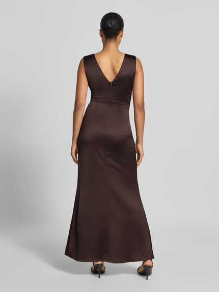 Frauenmodel trägt Abendkleid mit Raffungen von Rinascimento aus braunem Satin mit V-Ausschnitt und figurbetontem Schnitt, Ganzkörperansicht Rückansicht.