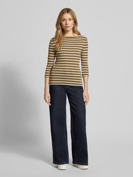 Frauenmodel trägt Slim Fit 3/4-Shirt aus reiner Baumwolle von Tommy Hilfiger mit Allover-Muster, gestreift, Logo-Stitching, U-Boot-Ausschnitt, 3/4-Arm, Feinstrick, Ganzkörperansicht von vorne.