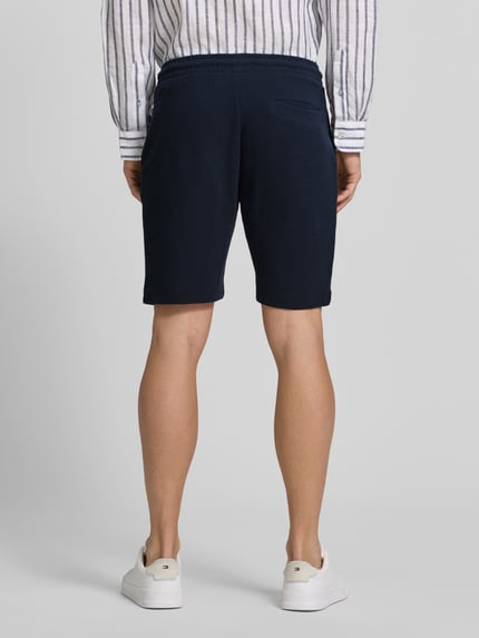 Männermodel trägt Shorts aus Baumwolle mit Strukturmuster von Christian Berg Men in Dunkelblau, Regular-Fit, elastischer Bund, Ganzkörperansicht Rückansicht