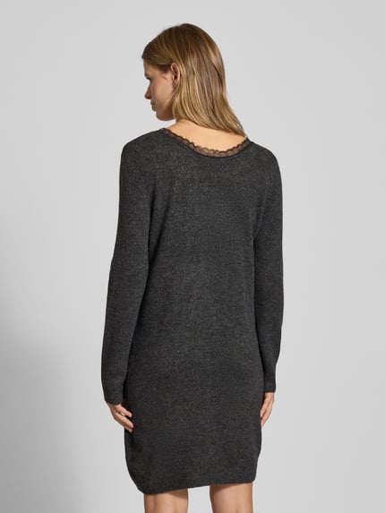 Frauenmodel trägt tailliertes, knielanges Strickkleid mit V-Ausschnitt, Spitzenbesatz, melierte Optik, Modell 'TAMMY' von Only, Ganzkörperansicht Rückansicht