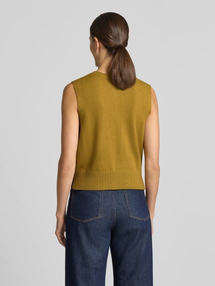 Frauenmodel trägt Strickweste aus Viskose-Mix mit Knopfleiste von Christian Berg Woman, Regular Fit, senfgelb, glatte Textur, Ganzkörperansicht Rückansicht.