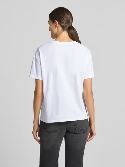 Frauenmodel trägt T-Shirt mit Motiv-Print und Strasssteinbesatz von Liu Jo White, reine Baumwolle, Boxy Fit, Rundhalsausschnitt, Rückenlänge 60 cm, Ganzkörperansicht Rückansicht.
