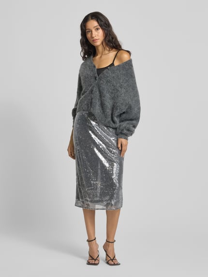 Frauenmodel trägt silbernen Midirock mit Pailletten Modell 'XSPARKLE' von Mango, Gerader-Schnitt, elastischer Bund, Gehschlitz, Ganzkörperansicht von vorne. Bundweite bei Größe S: 39 cm, Gesamtlänge: 77 cm.