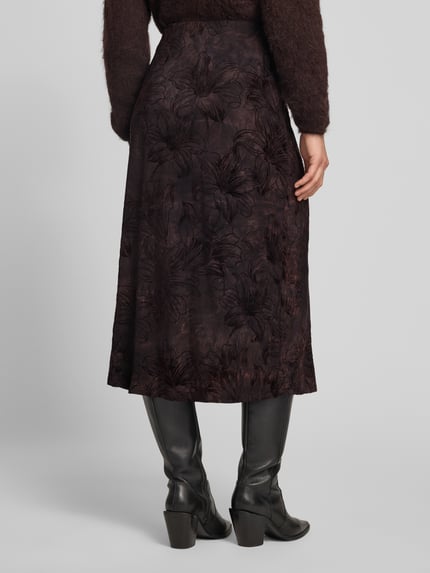 Frauenmodel trägt Midirock im Allover-Look Modell 'SESSOLANA' von FREE/QUENT, dunkle Töne, florales Muster, Material-Mix mit Stretch-Anteil, gerader Schnitt, Bundweite 37 cm, Länge 89 cm, Ganzkörperansicht Rückansicht.