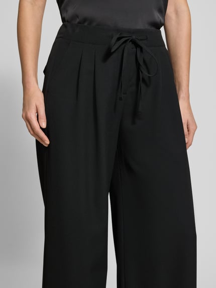 Frauenmodel trägt Stoffhose mit Tunnelzug von Luisa Cerano, schwarzer Material-Mix mit Viskose-Anteil, lockerer Schnitt, Nahaufnahme Oberkörper.