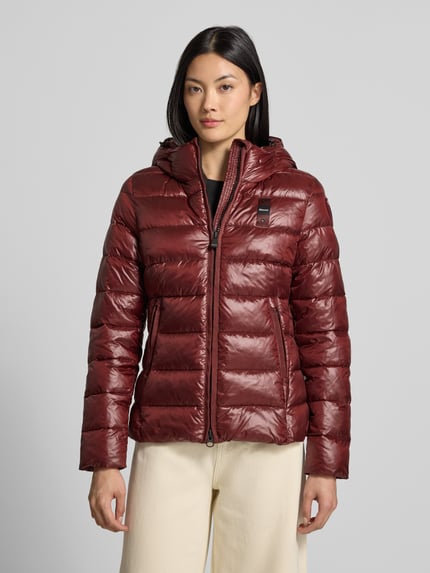 Frauenmodel trägt Jacke in Stepp-Optik Modell 'CAROLL' von Blauer USA in Bordeaux mit Kapuze, Zweiwege-Reißverschluss, Ganzkörperansicht von vorne.