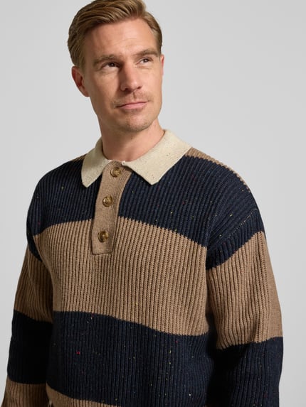Männermodel trägt Poloshirt mit gerippten Abschlüssen Modell 'Lotu' von WOODBIRD, breite Streifen in Blau und Beige, Nahaufnahme Oberkörper.