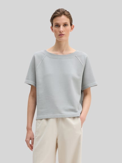 Frauenmodel trägt Regular Fit Sweatshirt aus reiner Baumwolle von Marc O'Polo, Optik: Unifarben, Label-Print, Rundhals, Kurzarm, Rumpfabschluss: Gerippt, Material: Reine Baumwolle, helle Farben, glatte Textur, Ganzkörperansicht von vorne.