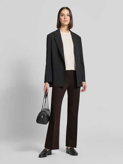 Frauenmodel trägt Schlaghose aus Viskose-Mix mit Bügelfalte von Rich & Royal, Dunkelbraun, Bootcut Fit, Ganzkörperansicht von vorne.