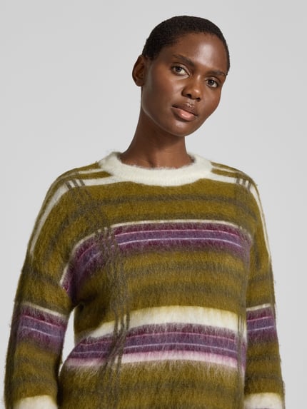 Frauenmodel trägt Strickpullover im Allover-Look Modell 'CHEA' von YAS in Olivgrün, Lila und Weiß, Materialmix mit Kaschmir-Anteil, Rundhalsausschnitt, Relaxed Fit, Nahaufnahme Oberkörper.