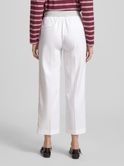 Vrouwenmodel draagt Wide Fit stoffen broek in 7/8-lengte model 'Sue' van TONI, katoenmix, persplooien, steekzakken, comfortbroekdesign, elastische band met tunnelkoord, kleur wit, bandwijdte maat 36: 34 cm, binnenbeenlengte maat 36: 66 cm, volledige lichaamsweergave achteraan.