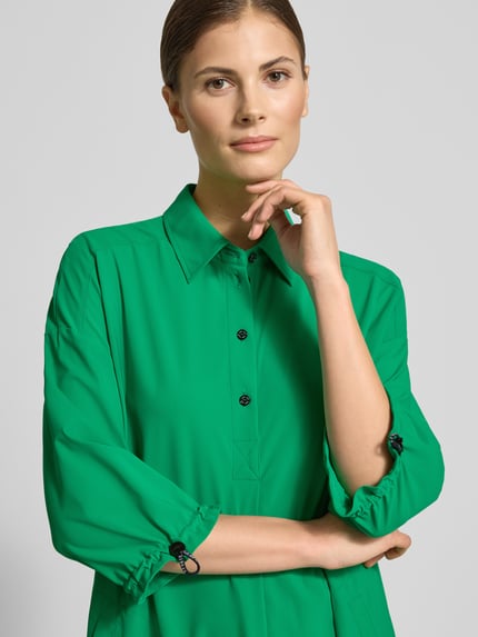 Frauenmodel trägt Knielanges Hemdblusenkleid mit Knopfleiste von Marc Cain in Grün, Material-Mix mit Stretch-Anteil, Gerader-Schnitt, Nahaufnahme Oberkörper.