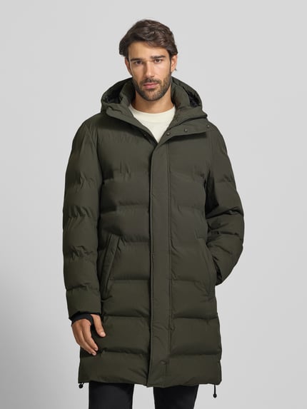 Männermodel trägt Steppmantel mit verdecktem Reißverschluss und Eingrifftaschen von MCNEAL in Olive, strukturierte Oberfläche, Ganzkörperansicht von vorne. Rückenlänge 100 cm, Schulterbreite 48 cm, Brustweite 59 cm, Ärmellänge 64 cm, Regular Fit, Kapuze.