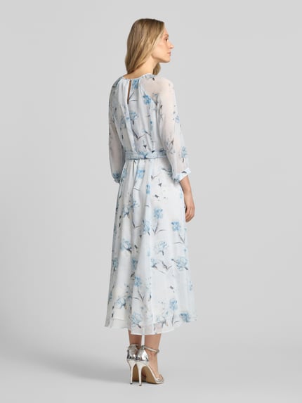 Vrouwenmodel draagt Midikleid met Bindegürtel van More & More, lichtblauw bloemmotief, getailleerd model, ronde hals met cut-out, strikceintuur, 3/4-mouwen, druppelvormige hals en ritssluiting op de rug, ruglengte maat 36: 128 cm, borstwijdte: 42 cm, mouwlengte: 58 cm, volledig opgenomen rugaanzicht.