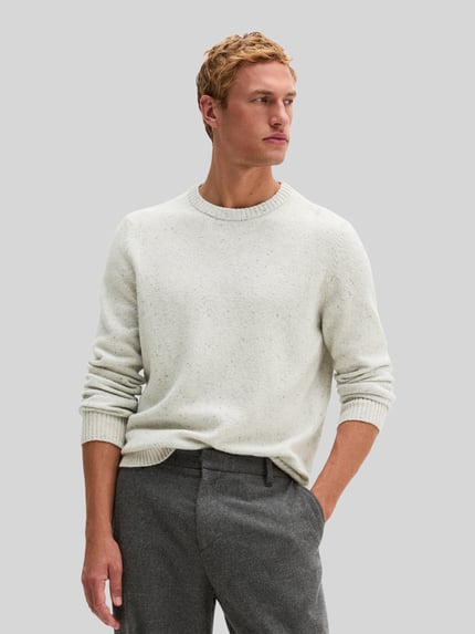 Männermodel trägt Pullover mit Logo-Detail von MARC O'POLO in heller Melange-Strickoptik, Struktur, Rundhals, Regular Fit, Ganzkörperansicht von vorne.