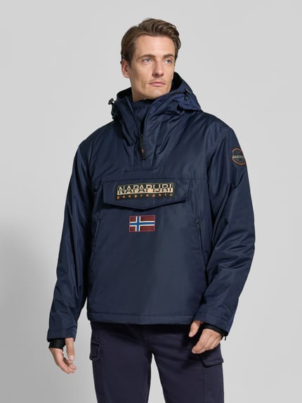Männermodel trägt Jacke mit Kapuze und kurzem Reißverschluss von Napapijri, dunkelblau, Label-Patches, gerader Schnitt, Nahaufnahme Oberkörper.