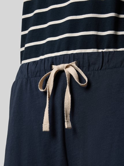Frauenmodel trägt Regular Fit Pyjama-Set aus reiner Baumwolle von Marc O'Polo, Oberteil gestreift, Hose uni mit elastischem Bund und Tunnelzug, Jersey-Material, Nahaufnahme Taillenbereich.