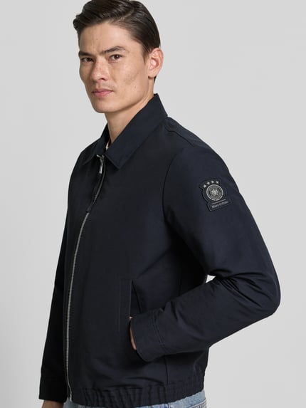 Männermodel trägt Regular Fit Blouson mit Label Patch - Marc O'Polo × DFB Travel Collection, Optik: Unifarben, Material: Baumwoll-Mix, Nahaufnahme Oberkörper.