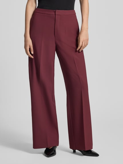 Frauenmodel trägt Wide Fit Hose mit Bügelfalten Modell 'Leya' von MOS MOSH in Dunkelrot, glatte Struktur, Nahaufnahme Oberkörperansicht, Damen Hose von MOS MOSH, Bügelfalten, Wide Fit, Haken- und Reißverschluss, Bundweite bei Größe 36: 62 cm, Innenbeinlänge bei Größe 36: 80 cm.