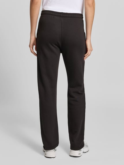 Vrouwenmodel draagt zwarte sweatpants uit mix van katoen en modal van Juvia, losse pasvorm, steekzakken, tunnelkoord, binnenbeenlengte 74 cm, bandwijdte 38 cm, geheel van achteren