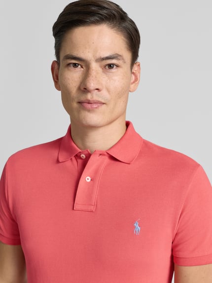 Männermodel trägt Poloshirt mit Label-Stitching von Polo Ralph Lauren in Rosa, reine Baumwolle, Slim Fit, Nahaufnahme Oberkörper.
