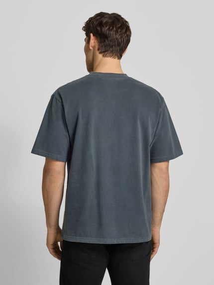 Männermodel trägt T-Shirt mit Rundhalsausschnitt Modell 'Liam' von Wood Wood, Baumwolle, dunkelgrau, lockere Passform, Ganzkörperansicht Rückansicht.