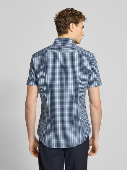 Männermodel trägt Slim Fit Business-Hemd aus Baumwolle mit Kentkragen von Jake*s, kariert, 1/2-Arm, Rückenlänge 79 cm, Ganzkörperansicht Rückansicht.