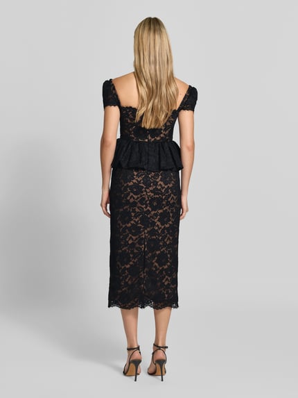 Frauenmodel trägt Abendkleid mit Spitzenpeplum von Self-Portrait in Schwarz mit floraler Spitzenstruktur, Rückansicht, Ganzkörperansicht.