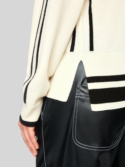 Kobieta nosi 'Pullover aus Wolle Alpaka mit Strukturlogo' od Marc Cain w melanżowej, dzianinowej optyce, oversize, z logo, kontrastowymi paskami, długim rękawem i bocznymi rozcięciami, detal tyłu swetra, ujęcie zbliżeniowe na dolną część pleców
