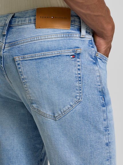 Männermodel trägt Slim Fit Straight Jeans aus katoenmix Modell 'DENTON' van Tommy Hilfiger, lichte blauwe wassing, detailopname achterkant, heren straight jeans van Tommy Hilfiger.
