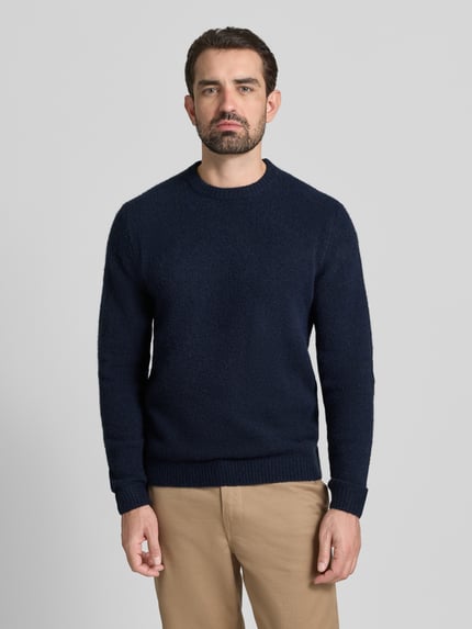Męski model nosi Sweter z dzianiny z prążkowanymi wykończeniami Model 'BLASIMON' od Jack & Jones Premium, mieszanka materiałów z dodatkiem wełny, luźny krój, okrągły dekolt, długość tyłu 64 cm, długość rękawów 69 cm, kolor granatowy i beżowy, tekstura miękka; całkowity widok od przodu.
