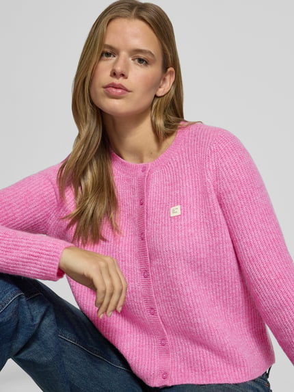 Frauenmodel trägt Cardigan mit Label-Patch von ONLY in Rosa, Strickoptik mit Rundhalsausschnitt, Nahaufnahme Oberkörper.