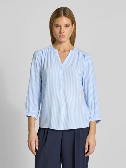 Kobiece model nosi Comfort Fit Langarmbluse aus reiner Viskose od Tom Tailor, efekt: wzór na całej powierzchni, krój comfort fit, kształt kołnierza: stójka, dekolt: tunika, zapięcie: krótka listwa guzikowa, rękaw: rękaw o dł. 3/4, zakończenie rękawów: mankiet, materiał: czysta wiskoza, jasnoniebieskie paski, tekstura lekka, całkowity widok z przodu