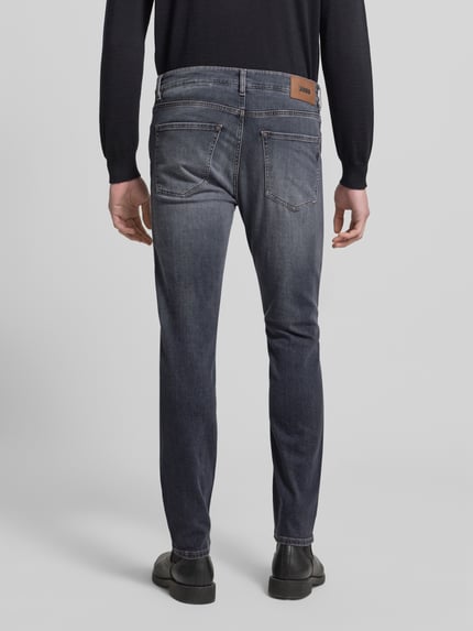 Męski model nosi Slim Fit Jeans aus Baumwoll-Mix Modell 'DELAWARE' od BOSS, stylizowana na denim, krój slim fit, naszywka z logo, nity, 5 kieszeni, mieszanka bawełny, Ganzkörperansicht Rückansicht.