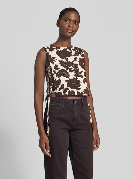 Frauenmodel trägt Blusentop aus Viskose-Mix mit seitlicher Schnürung von Mango, Allover-Look, Regular-Fit, Rundhalsausschnitt, Ganzkörperansicht von vorne. Rückenlänge bei Größe S: 42 cm.