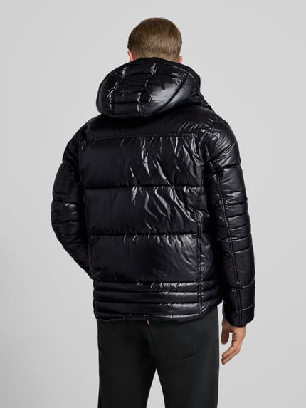 Männermodel draagt Regular Fit gewatteerd jack met capuchon van Tom Tailor in effen zwart met labelpatch en steekzakken, Ganzkörperansicht Rückansicht.