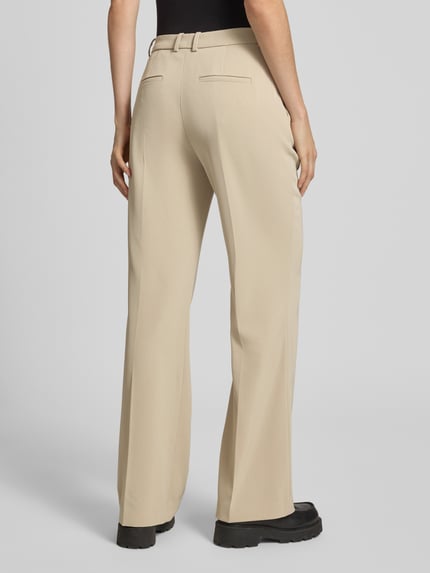 Modelka nosi Hose mit Bügelfalten Modell 'ARGUE' od Drykorn, kolor beżowy, krój regular fit, materiał z domieszką stretchu, szyte kanty, szerokość w rozmiarze 27/34: 40 cm, długość nogawki od wewnątrz: 82 cm, widok całej sylwetki z tyłu.