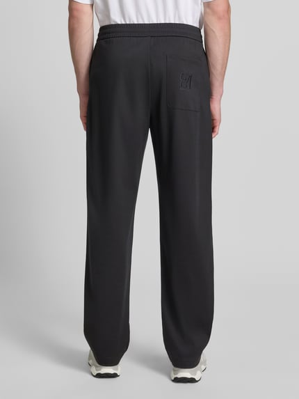 Männermodel trägt Sweatpants mit elastischem Bund von Emporio Armani aus Lyocell-Mix mit Viskose-Anteil, Relaxed-Fit und Eingrifftaschen, Ganzkörperansicht Rückansicht.
