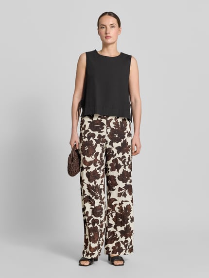 Frauenmodel trägt Stoffhose aus Viskose-Mix mit Eingrifftaschen Modell 'KARINA' von KARINA, floral gemustert, Wide Fit, Ganzkörperansicht von vorne.