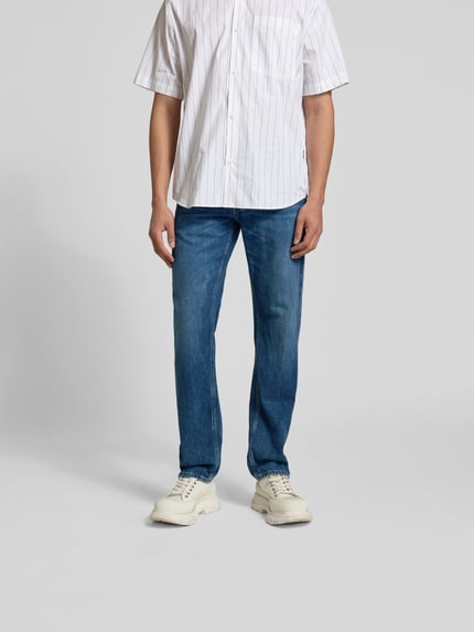 Männermodel trägt Straight Fit Jeans mit Logo-Patch von Closed aus reiner Baumwolle, 5-Pocket-Design, blaue Farbe, Ganzkörperansicht von vorne.