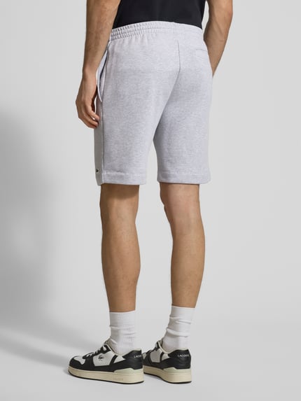 Männermodel trägt Regular Fit Sweatshorts aus Baumwoll-Mix von Lacoste in hellgrau meliert, elastischer Bund, unifarben, Ganzkörperansicht Rückansicht.
