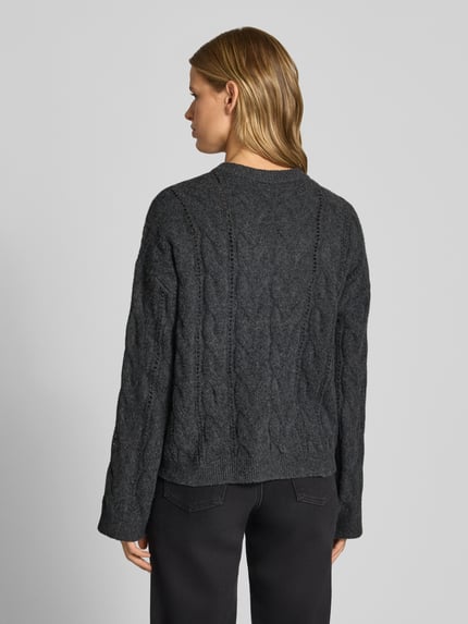 Modelka kobieca nosi ciemnoszary Relaxed Fit Pullover mit Rundhalsausschnitt Modell 'KATHY' od PIECES, sweter o grubym splocie, tekstura pleciona, widok całej sylwetki z tyłu, damski sweter.