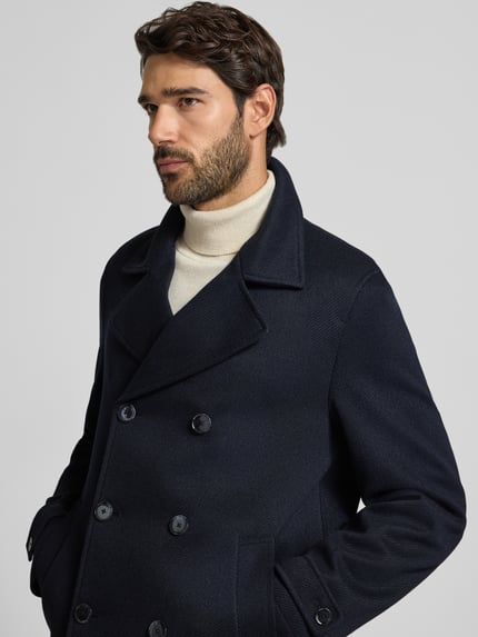 Männermodel trägt Jacke mit Reverskragen und Ärmelriegeln von MCNEAL, dunkelblau, Zweireiher, Knopfverschluss, Nahaufnahme Oberkörper.