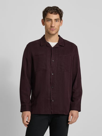 Männermodel trägt Hemdjacke mit Knopfleiste von CK Calvin Klein in dunklem Bordeauxrot, reine Lyocellstruktur, lockerer Schnitt, Nahaufnahme Oberkörper.